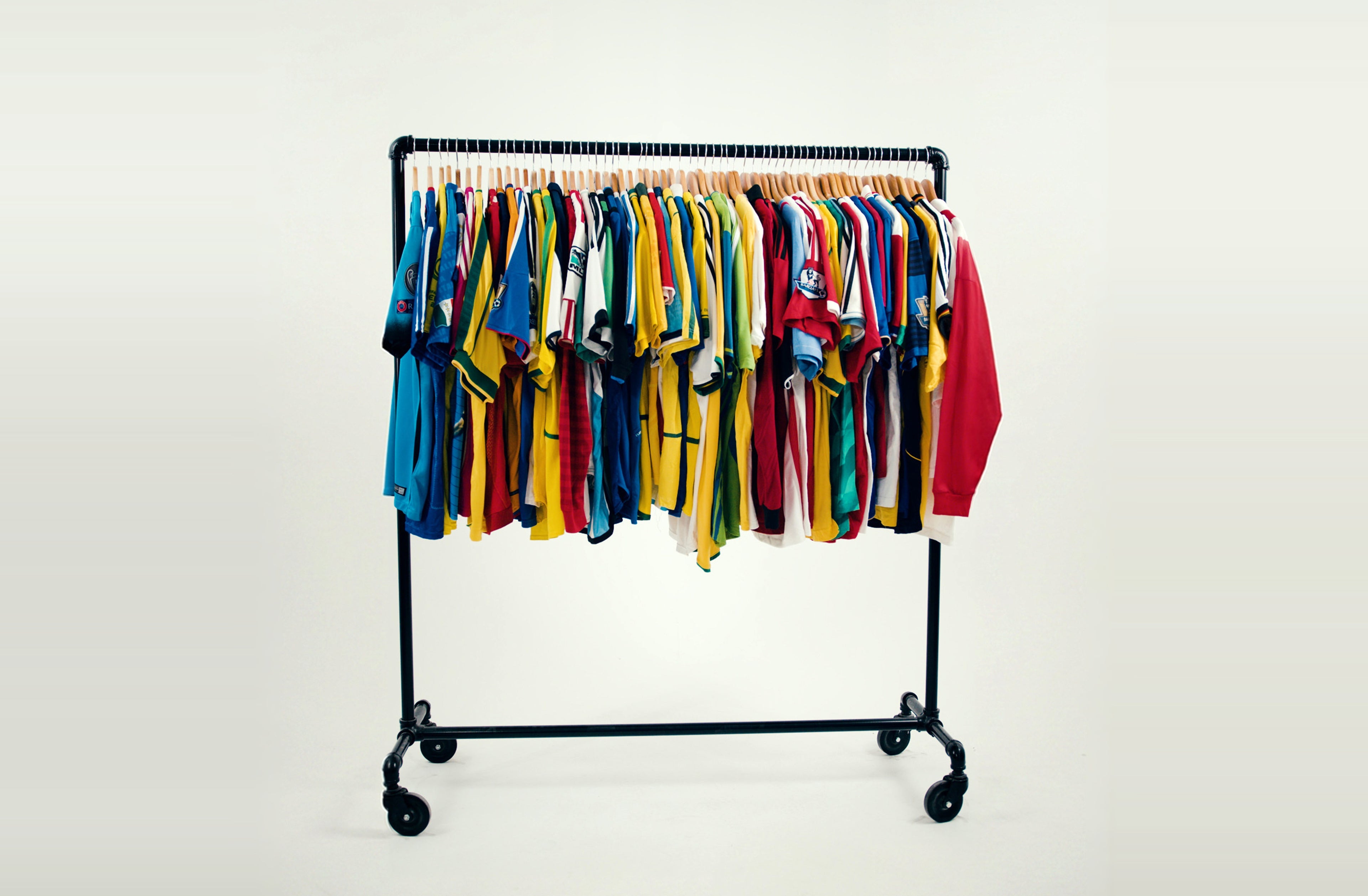 Rack of colorful vintage soccer jerseys against a light grey studio backdrop